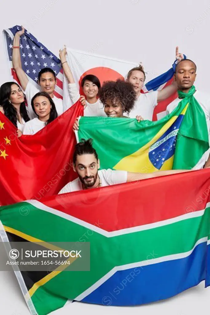 London, UK. Group of multi_ethnic friends holding various national flags against white background