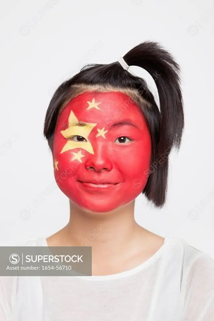 London, UK. Portrait of young Asian woman with Chinese flag painted on face against white background
