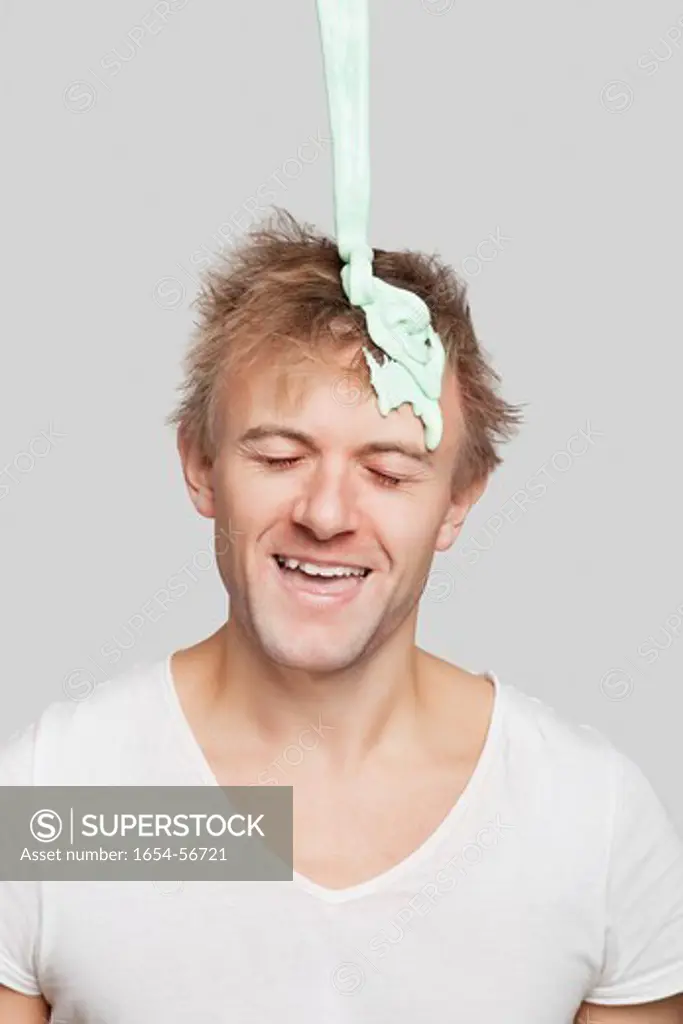 London, UK. Paint falling on young Caucasian man's head against gray background