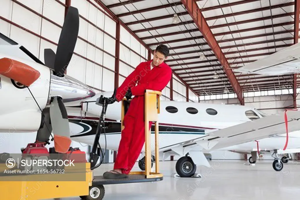 Palm Springs, California, USA. Young male aviation mechanic repairing airplane in airplane hangar