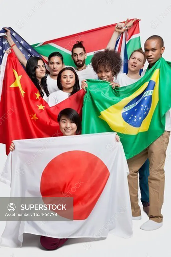 London, UK. Group of multi_ethnic friends holding various national flags against white background