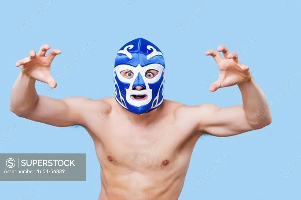 London, UK. Portrait of topless man in wrestling mask gesturing over gray background