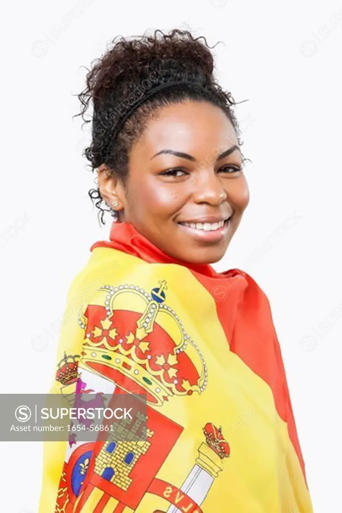 London, UK. Portrait of young woman wrapped in Spanish flag over white background