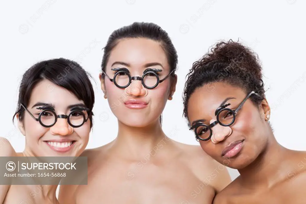 London, UK. Portrait of young multi_ethnic women wearing groucho glasses over white background