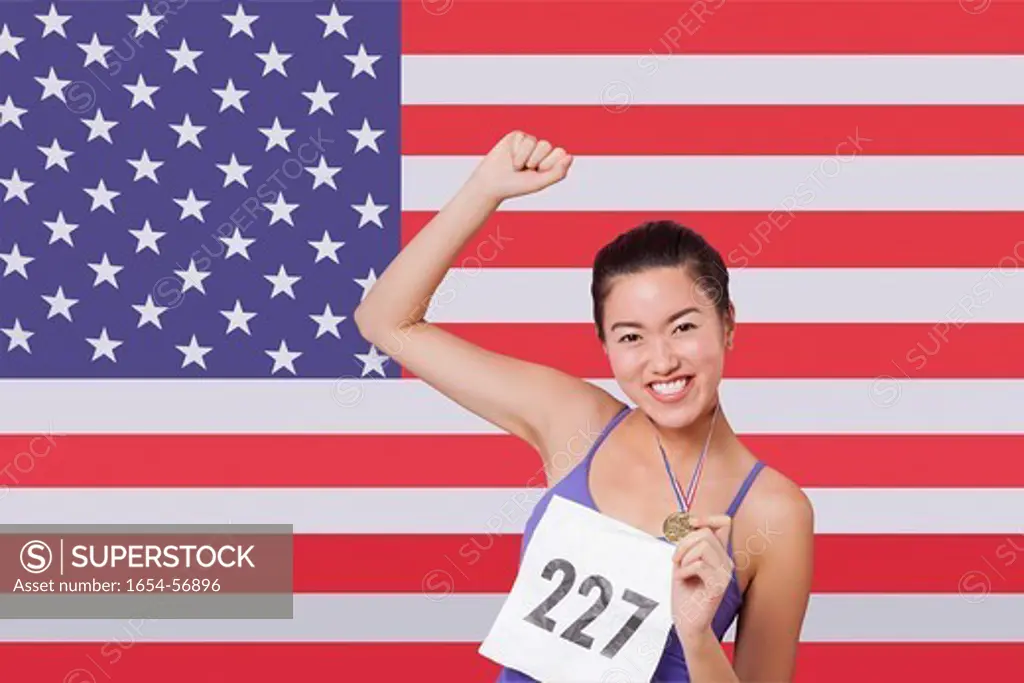 London, UK. Portrait of smiling young female medalist standing against American flag