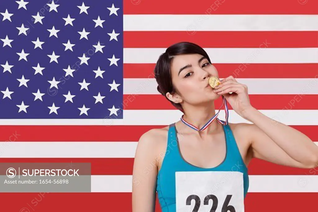 London, UK. Portrait of smiling young female medalist standing against American flag