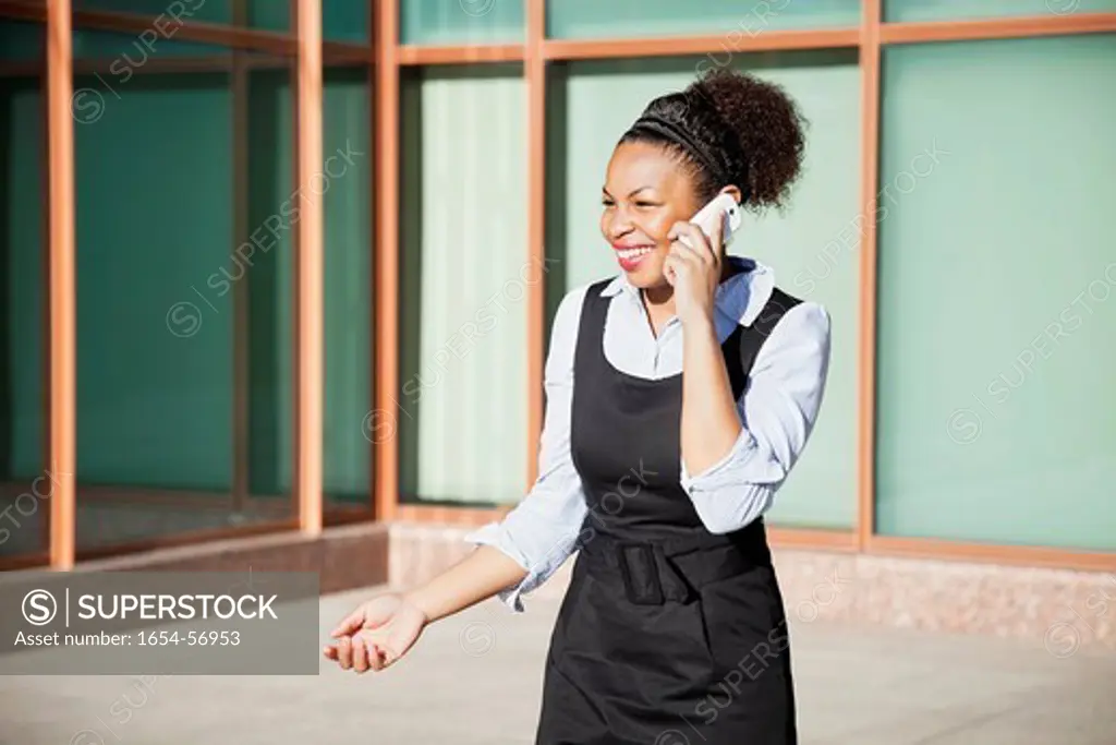 London, UK. Cheerful young woman in formals using mobile phone