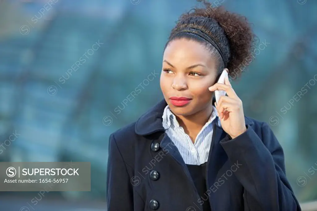 London, UK. Beautiful young woman in formals using mobile phone