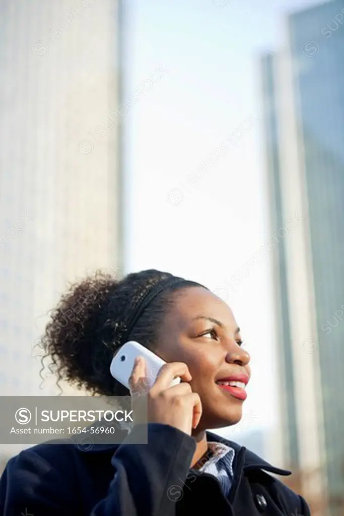 London, UK. Smiling African American young woman using mobile phone