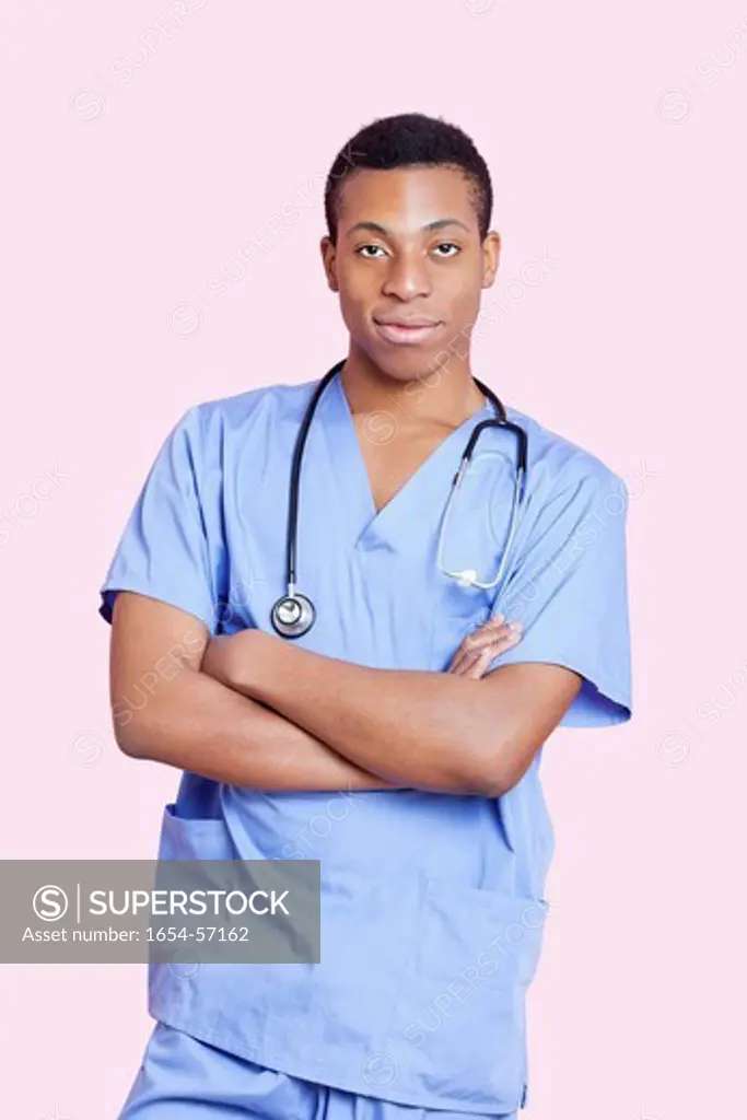 London, UK. Portrait of mixed race male surgeon with arms crossed over pink background