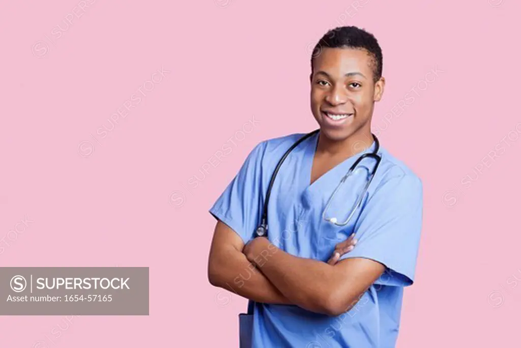 London, UK. Portrait of mixed race male surgeon with arms crossed over pink background