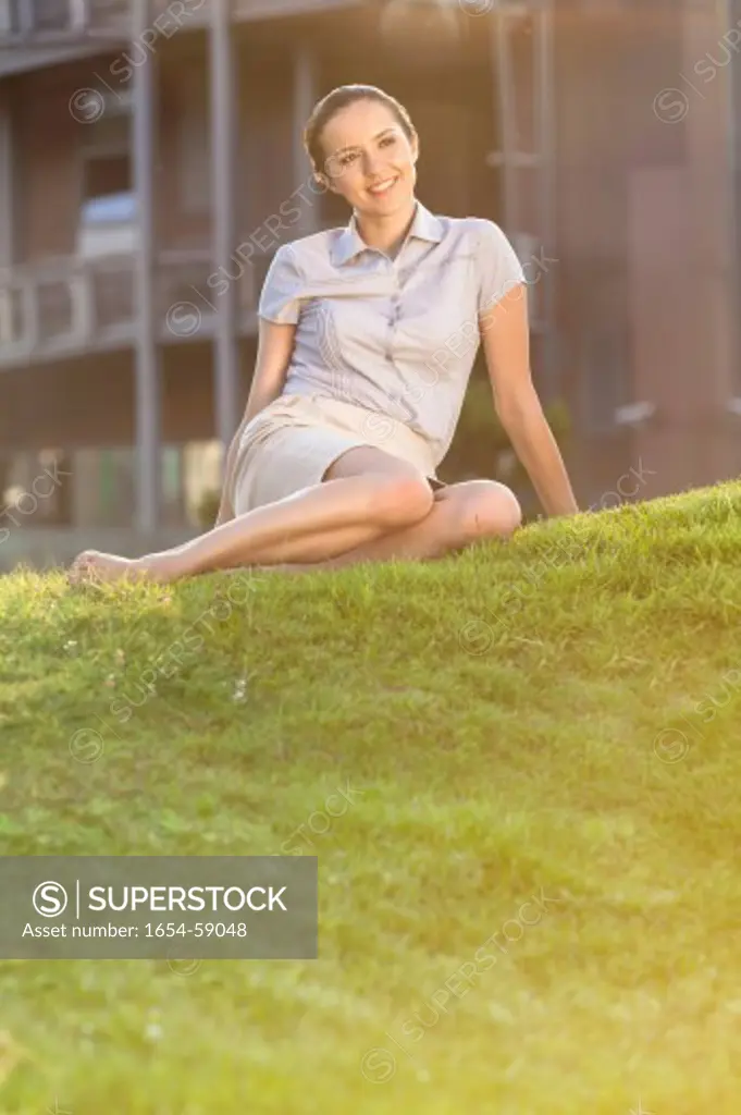 Smiling young businesswoman relaxing in office lawn