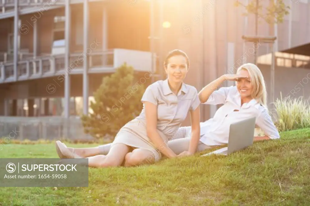 Young businesswomen with laptop relaxing on office lawn
