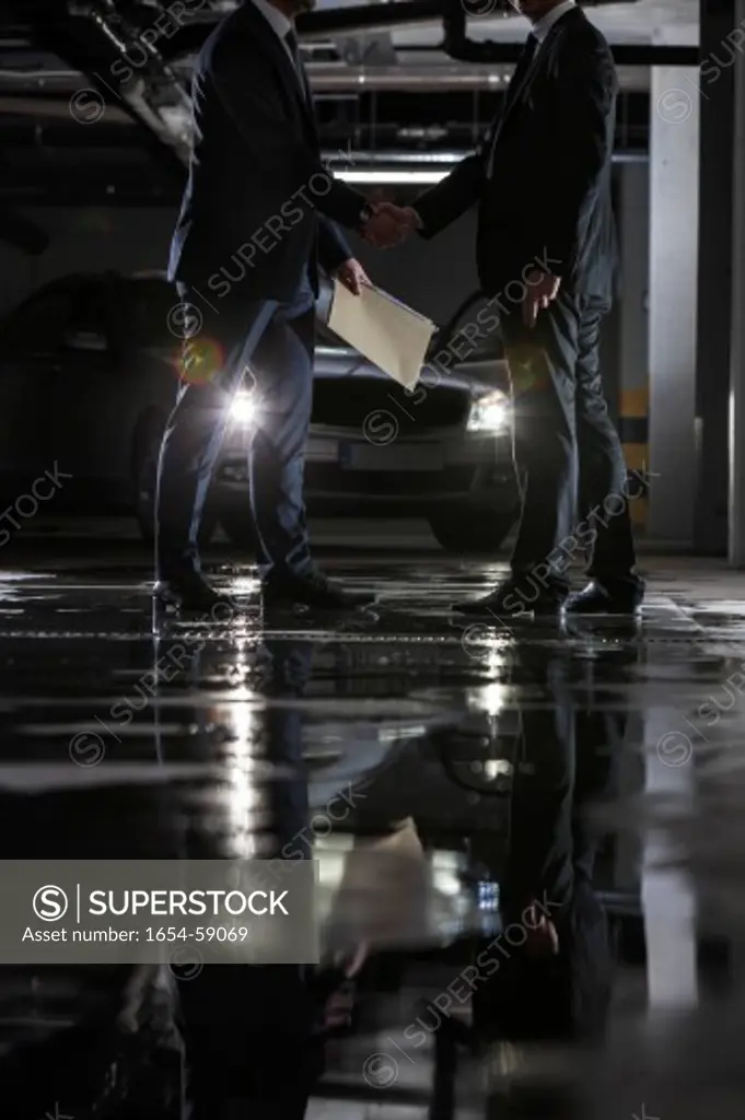 Low section of businessmen conducting suspicious business in parking lot