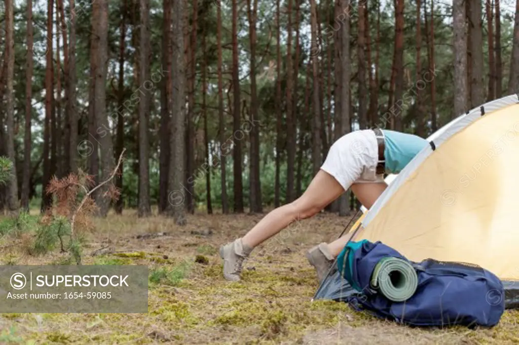Low section of woman entering tent in forest