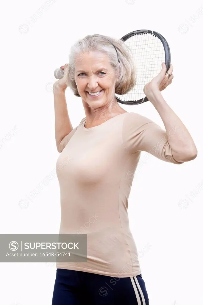 Portrait of senior woman holding tennis racket over her shoulder against white background