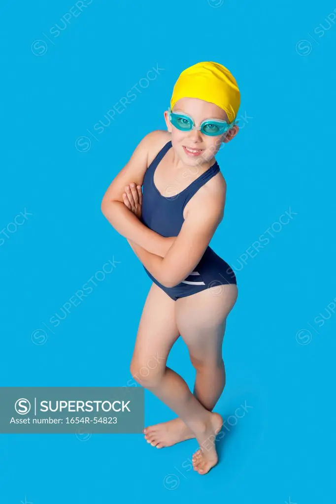 Portrait of a confident young girl in swimwear over blue background