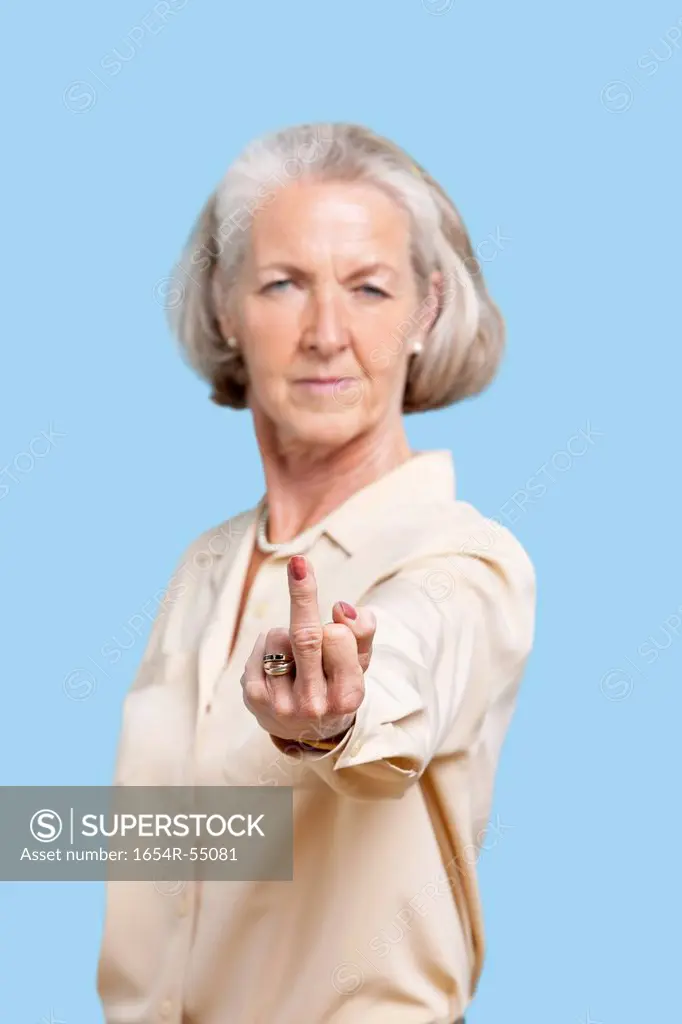 Portrait of senior woman in casuals making rebellious gesture against blue background