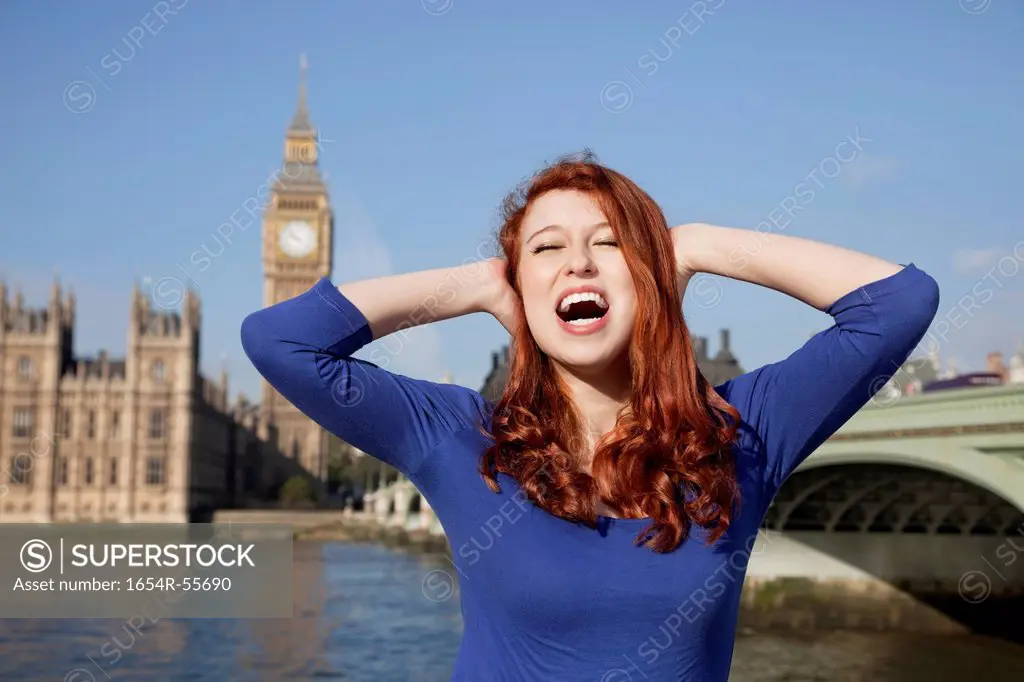 Angry young woman with hands on head screaming against Big Ben clock tower, London, UK