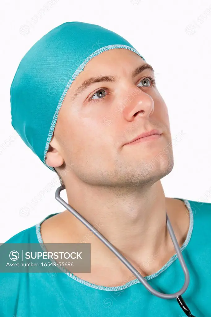 Young male surgeon in scrubs looking away against white background