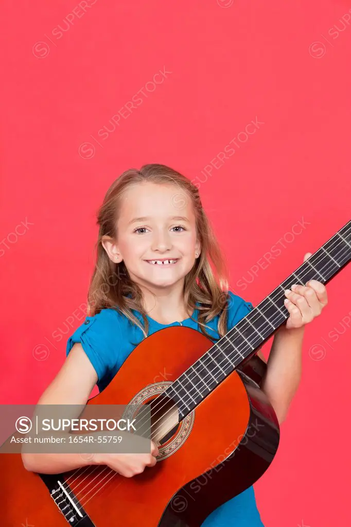 Portrait of girl playing guitar against red background
