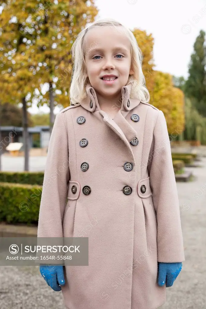 Portrait of cute little girl in winter coat standing at park