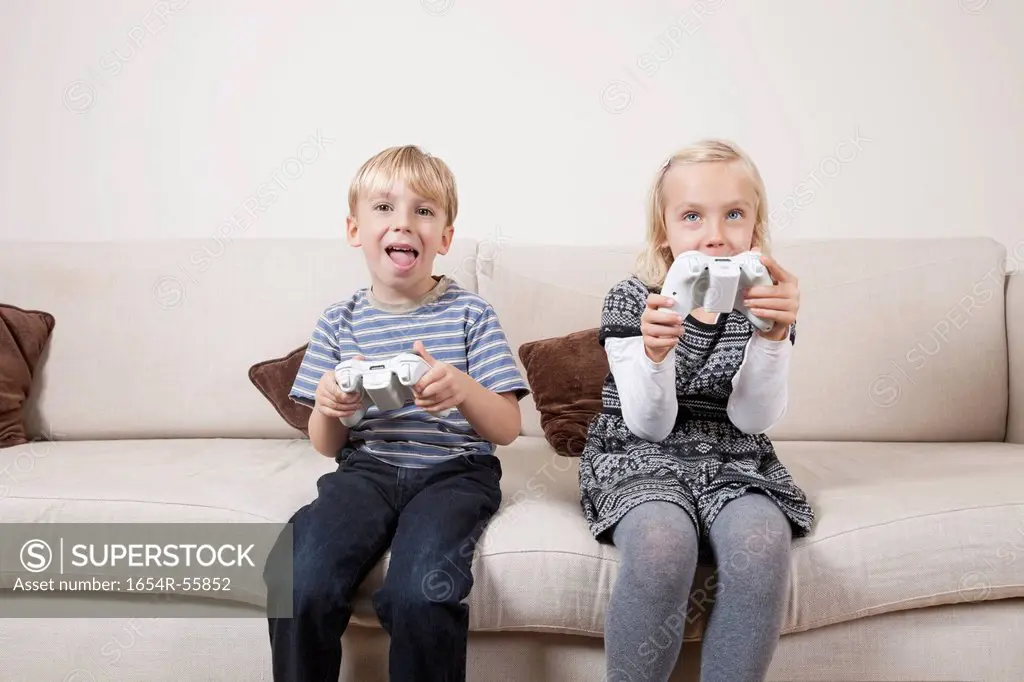 Happy brother and sister playing video game on sofa