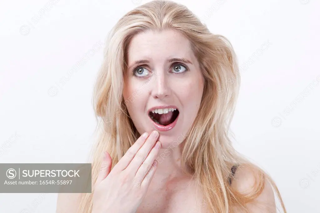 Surprised young woman with mouth open against white background