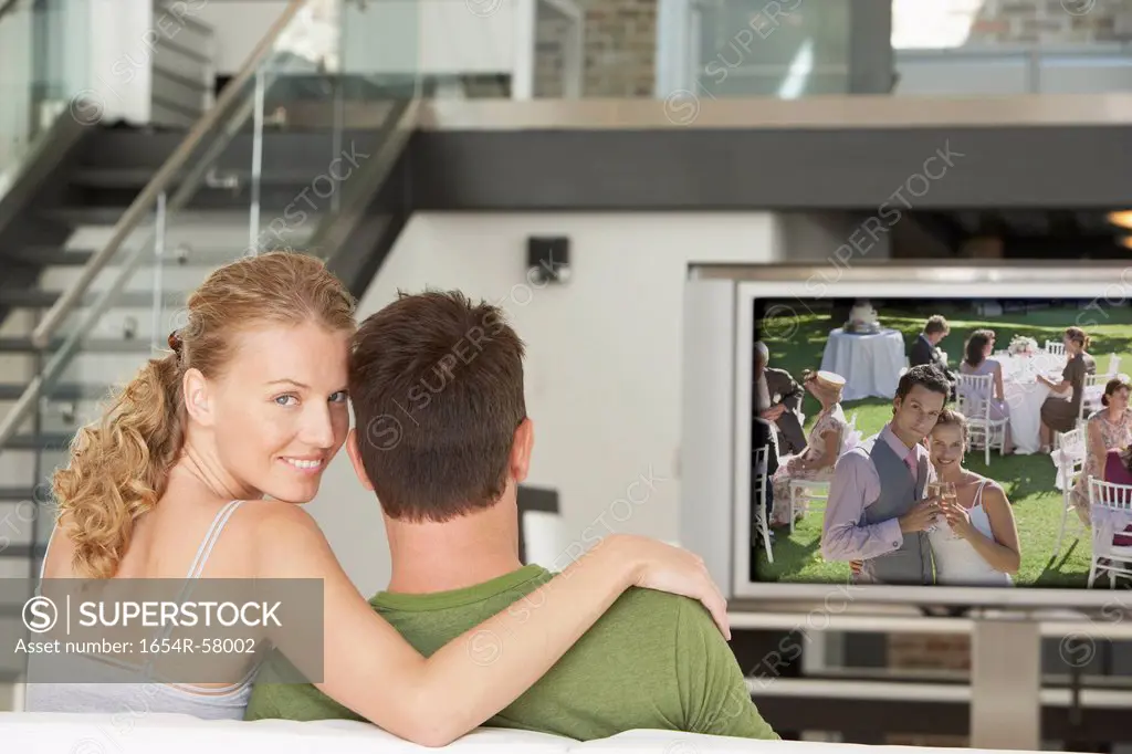 Portrait of young Caucasian woman with man watching movie on television in living room