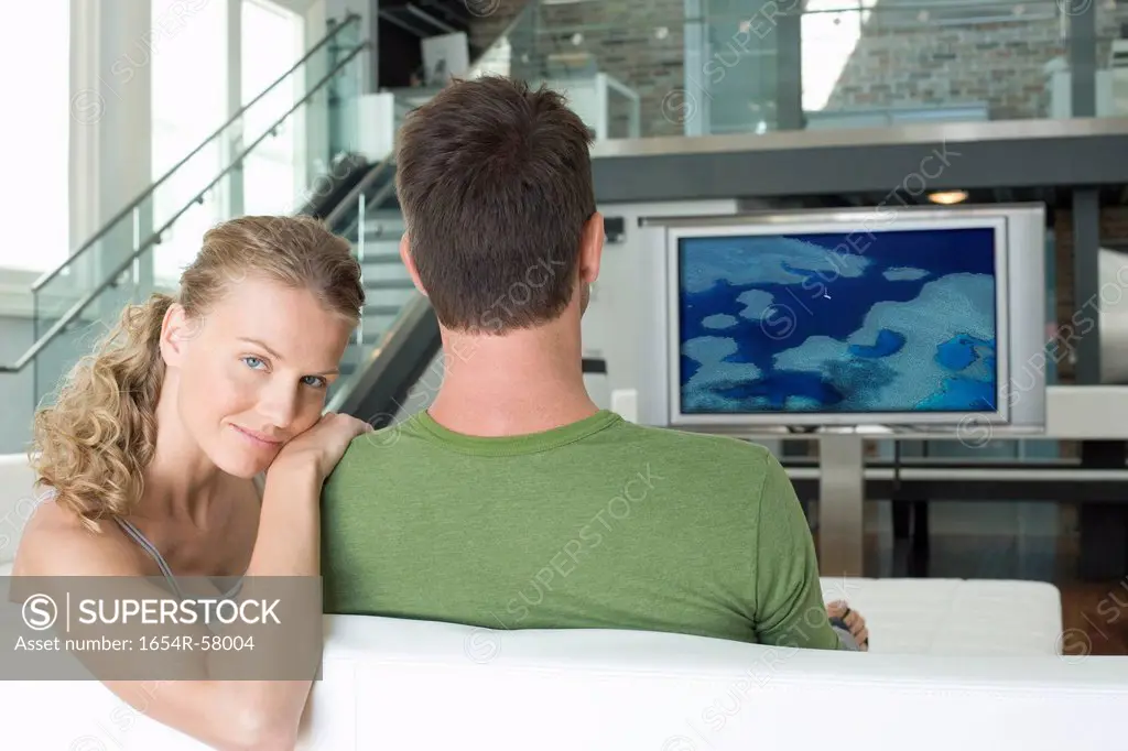 Portrait of young Caucasian woman with man watching television in living room