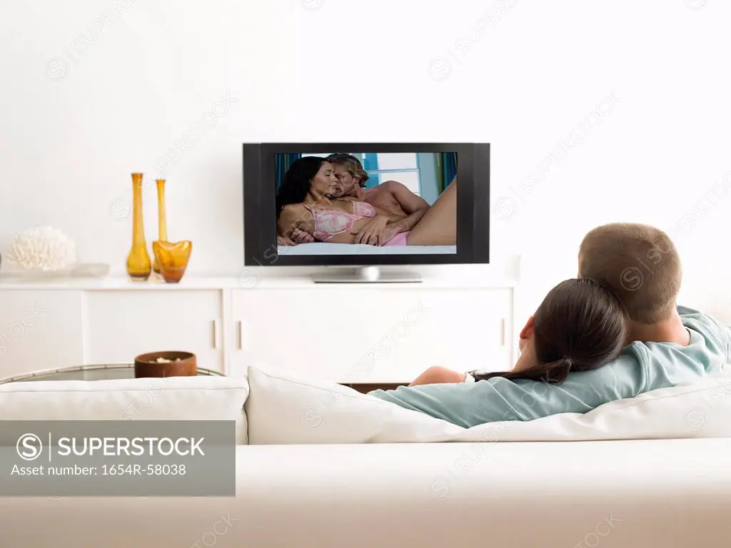 Back view of affectionate couple on sofa watching television