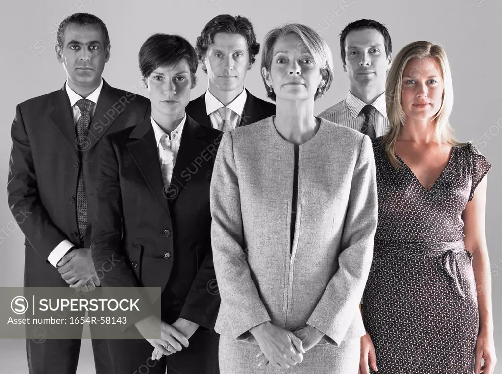 Ambitious businesswoman with team of professionals against gray background