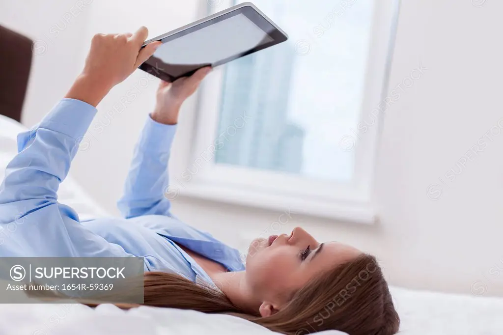 Beautiful woman using tablet computer on her bed