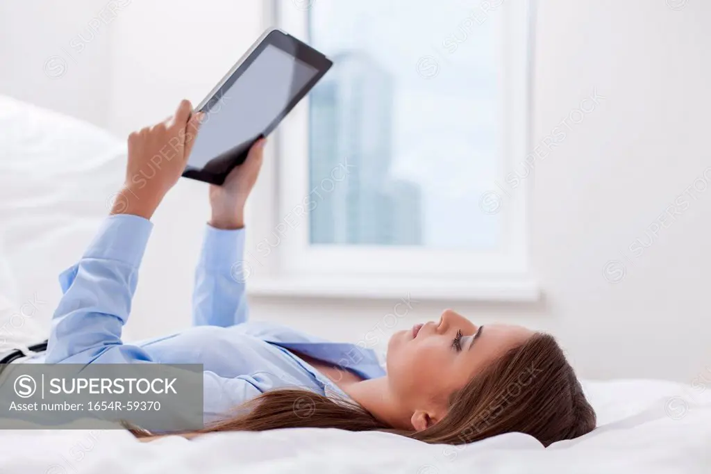 Beautiful woman using tablet computer on her bed
