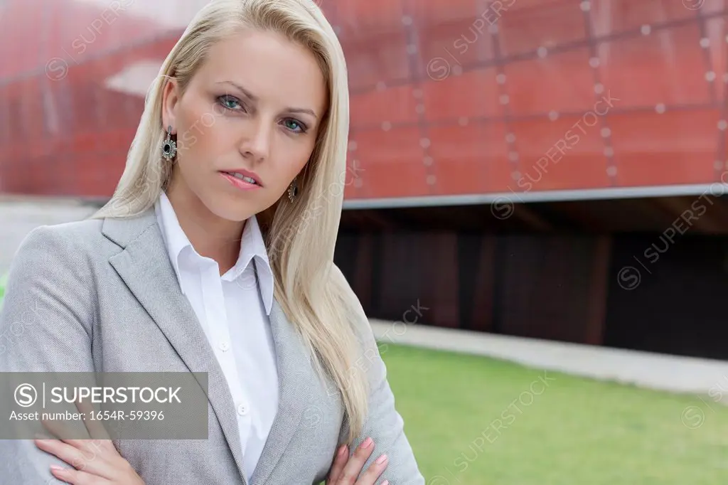 Close-up portrait of confident businesswoman against office building