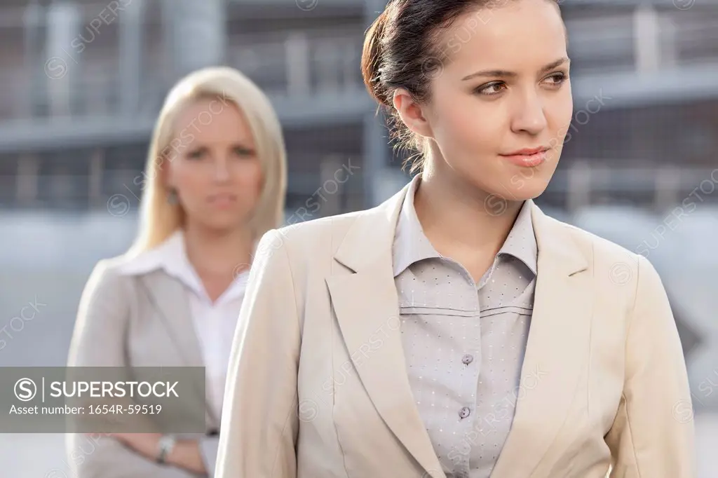 Young businesswoman looking away with female colleague in background