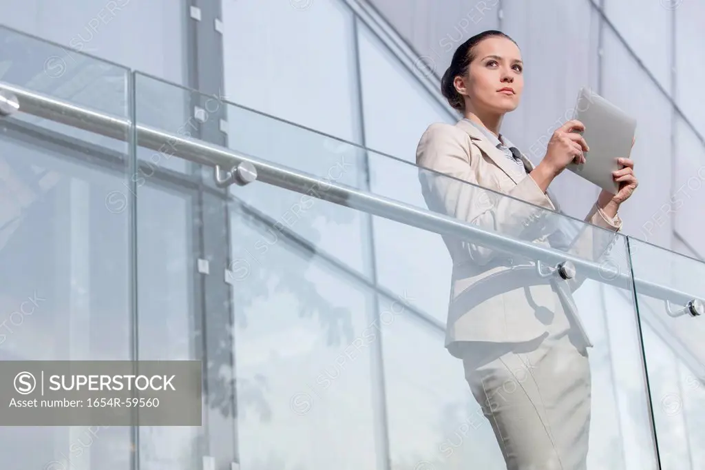Beautiful young businesswoman holding tablet computer at office railing