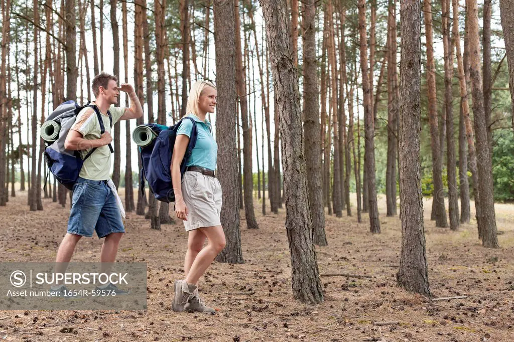 Full length of happy young couple trekking in forest