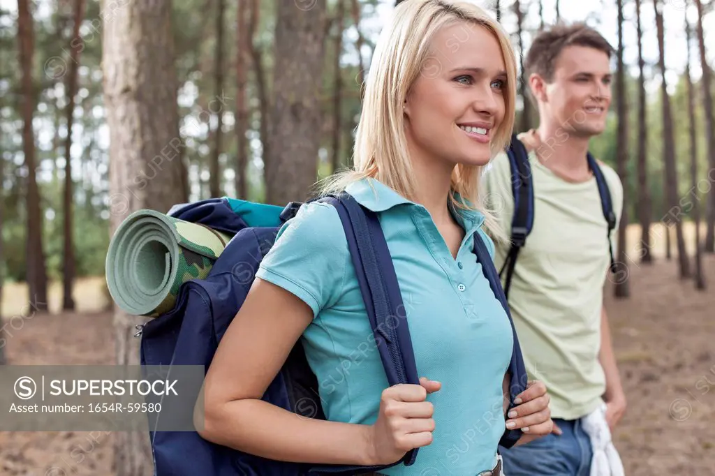 Beautiful young backpacker with man trekking in forest