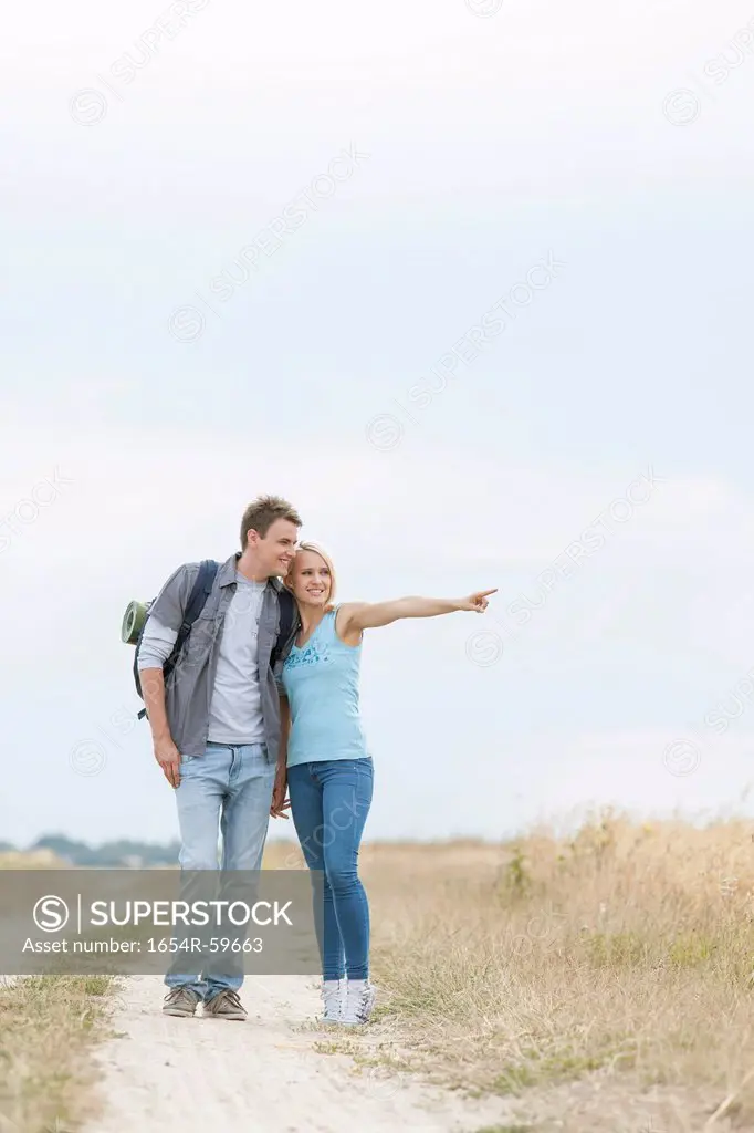 Young woman showing something to man while standing on trail at field