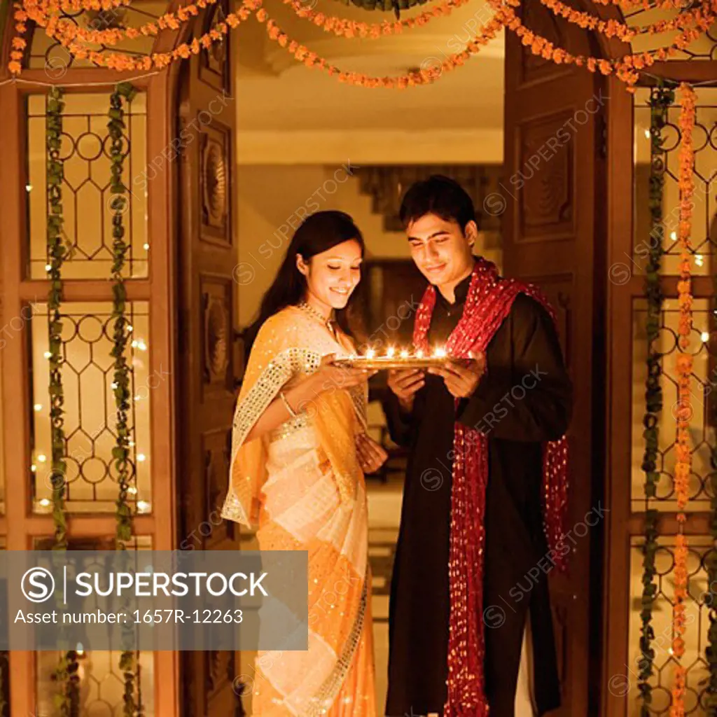 Young couple holding oil lamps in a plate