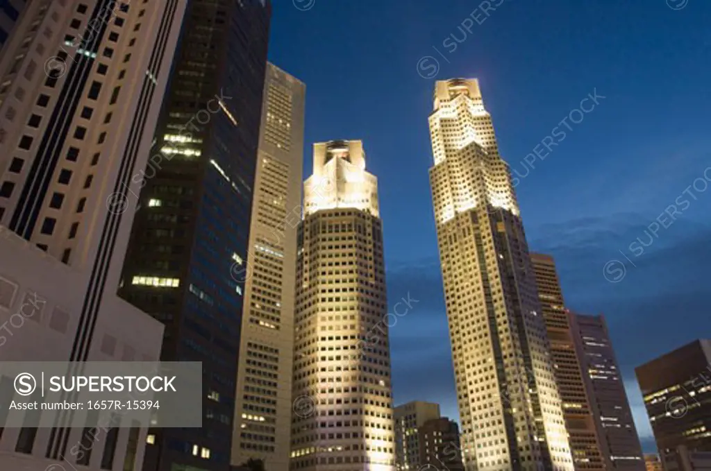 Low angle view of skyscrapers lit up at dusk, Singapore