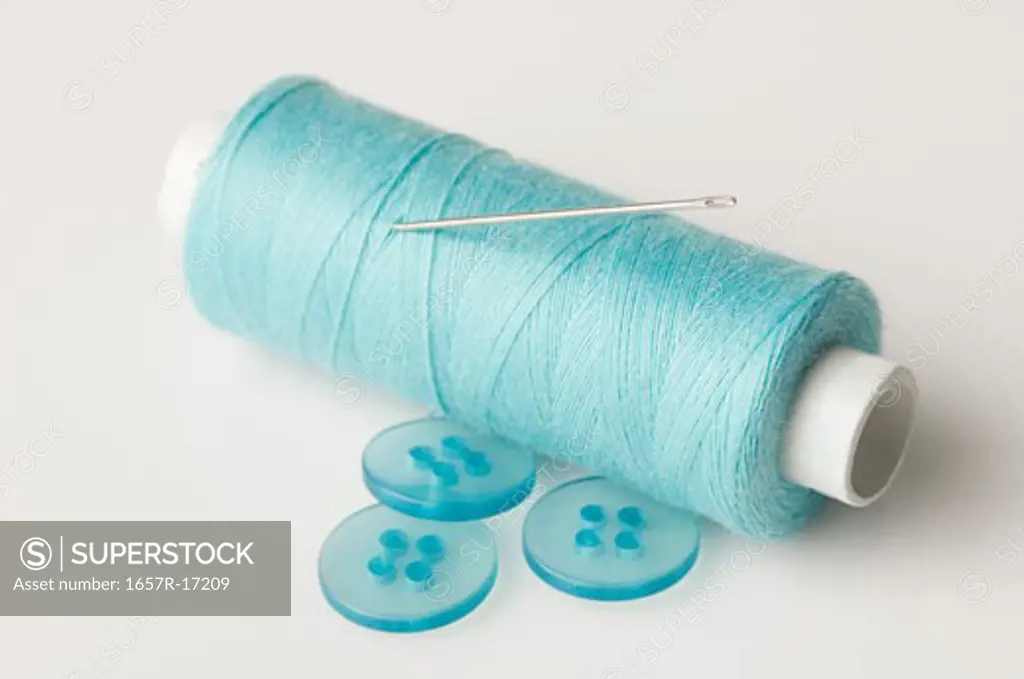 Close-up of buttons and a needle with a spool of thread