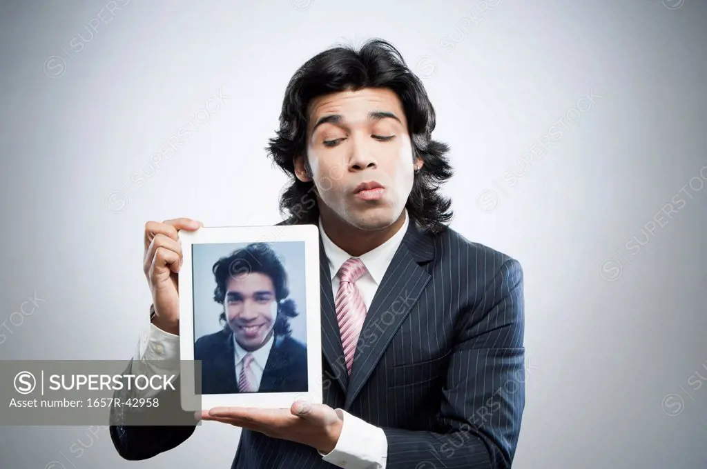 Businessman holding a digital tablet with his picture on it