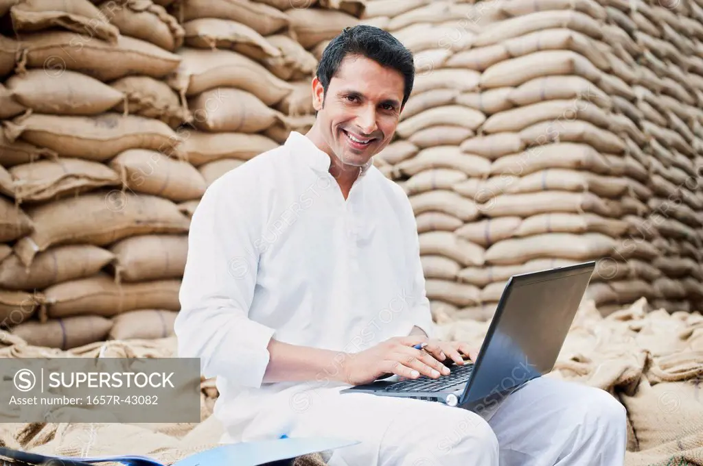 Man using a laptop in a grains market, Anaj Mandi, Sohna, Gurgaon, Haryana, India