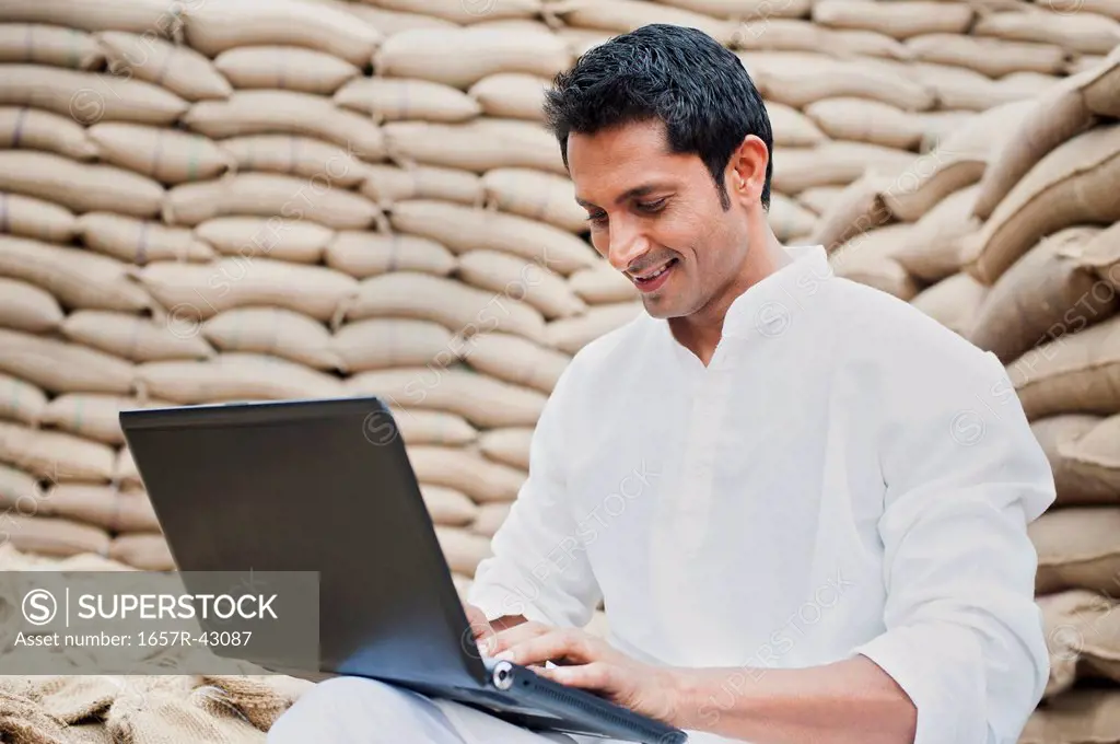 Man using a laptop in a grains market, Anaj Mandi, Sohna, Gurgaon, Haryana, India