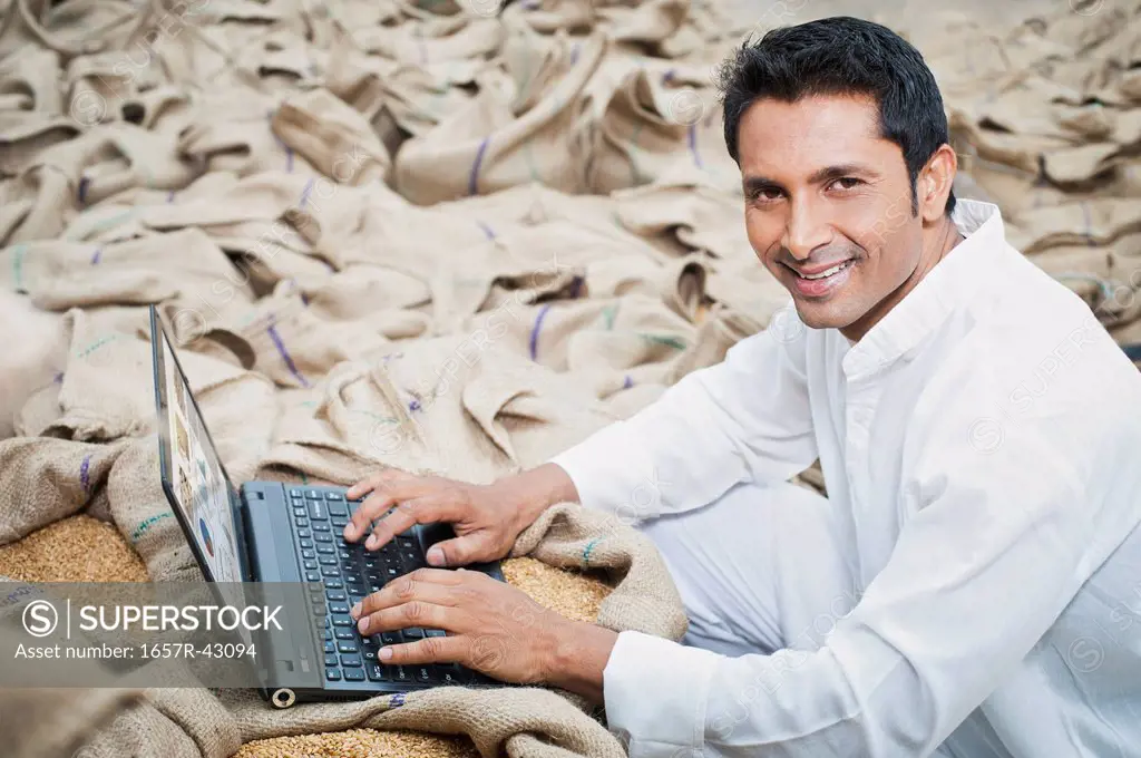 Man working on a laptop in a grains market, Anaj Mandi, Sohna, Gurgaon, Haryana, India