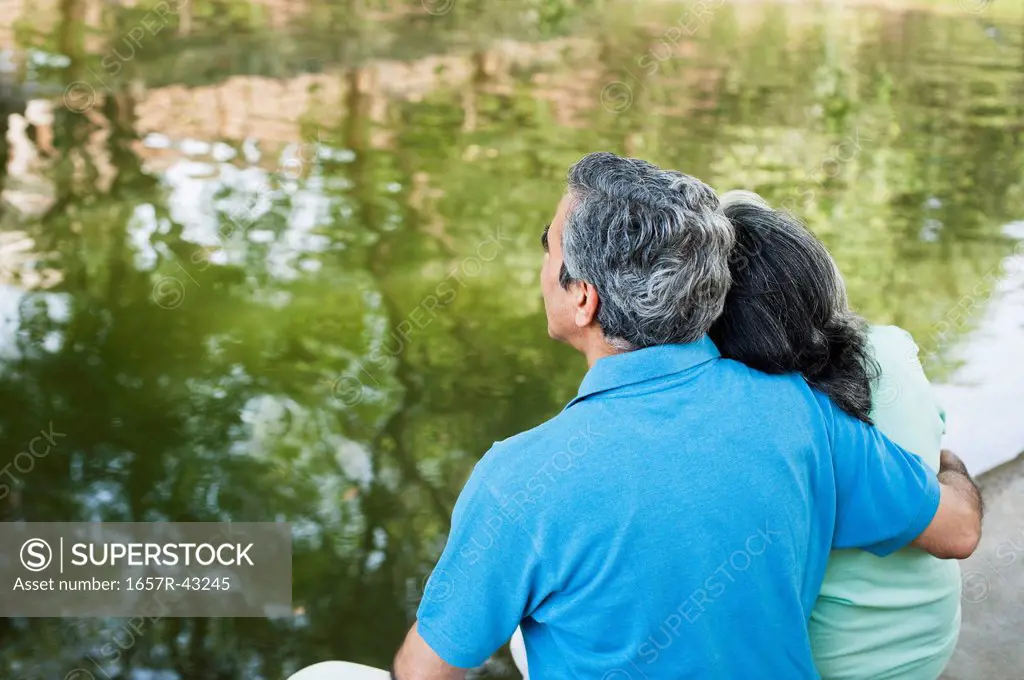 Mature couple sitting in a park at the lakeside, Lodi Gardens, New Delhi, India