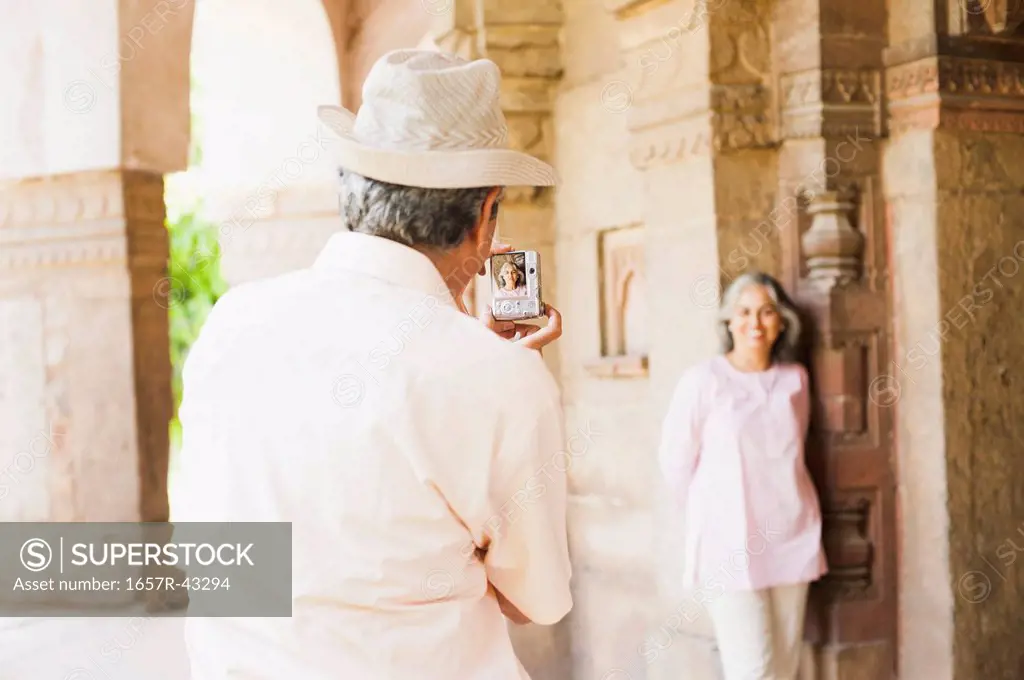 Man taking picture of his wife with a digital camera at a mausoleum, Lodi Gardens, New Delhi, India