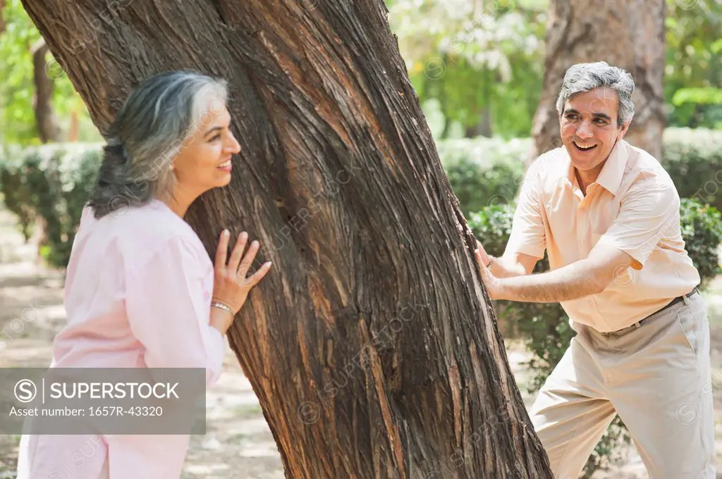 Mature couple playing hide and seek in a park, Lodi Gardens, New Delhi, India